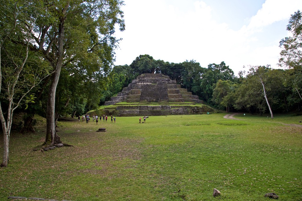 Central and South American Ruins Image: A group of people is dwarfed by a pyramidical structure in the background, and the surrounding forest.