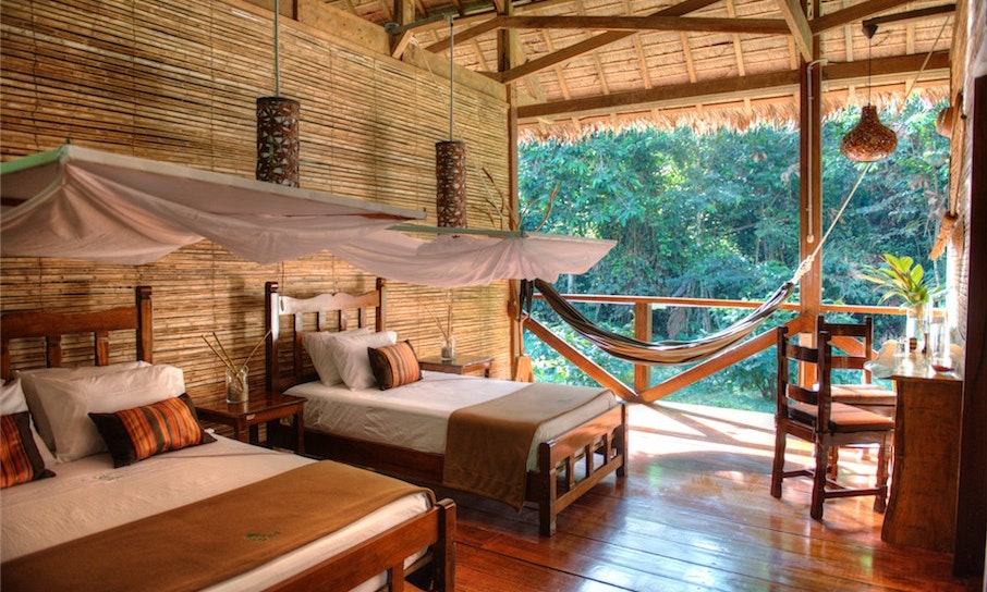 Seriously—you have a private en suite hammock. Peruvian Amazon Image: Photograph of a suite with two beds in an incredibly open thatched roof 'suite.'