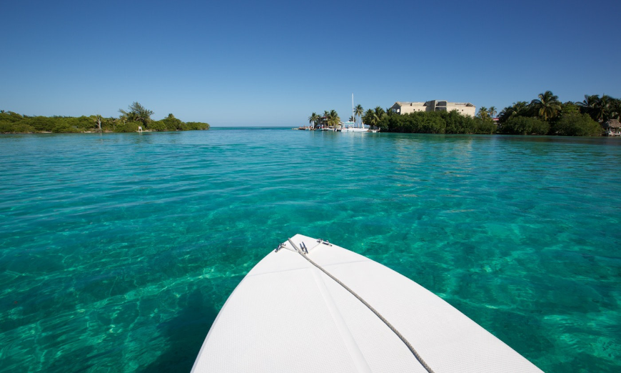 Best Beaches for Swimming in Belize Image: View of turquoise waters and neighboring islands as seen from the bow of a boat or paddle board.