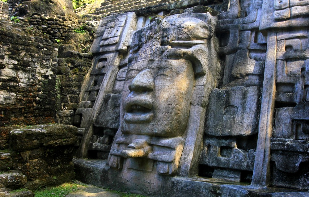 Central and South American Ruins Image: An oversized statue of a face is carved into a larger structure.