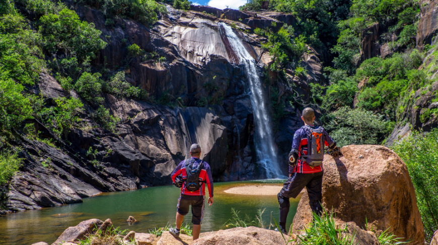 Planning activities during your holiday? Don't just rush through your list. Pause to take it all in. Best time to visit Central America Image: Two men with shaved heads have their backs to the camera as they look on at a waterfall; they are dressed in long sleeved outdoor apparel, and are carrying backpacks.