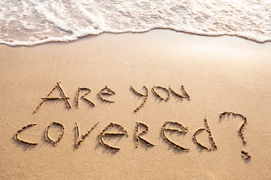 Everyone needs a friend—especially in travel. Booking A Vacation Online Image: The question 'Are you covered?' is written in the sand on a beach, with a wave coming in nearby.