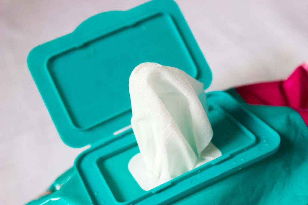 Keep hands and surfaces clean for a fun and healthy holiday. Family Adventure Image: A wet wipe is popping out of a turquoise container.