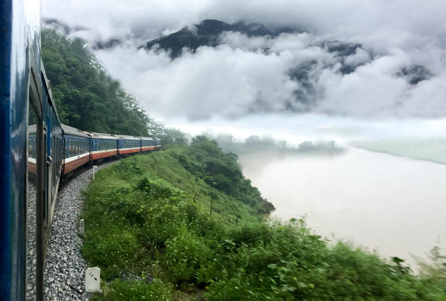 Make the most of your journey to Sapa—look out the window. Is Sapa Worth Visiting Image: A train travels through greenery and mist.