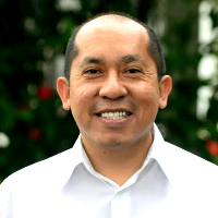 nywhere Peru's dashing manager Cesar Nizama. Mr. Nizama smiles in his white button-down shirt, with red and green foliage behind him.