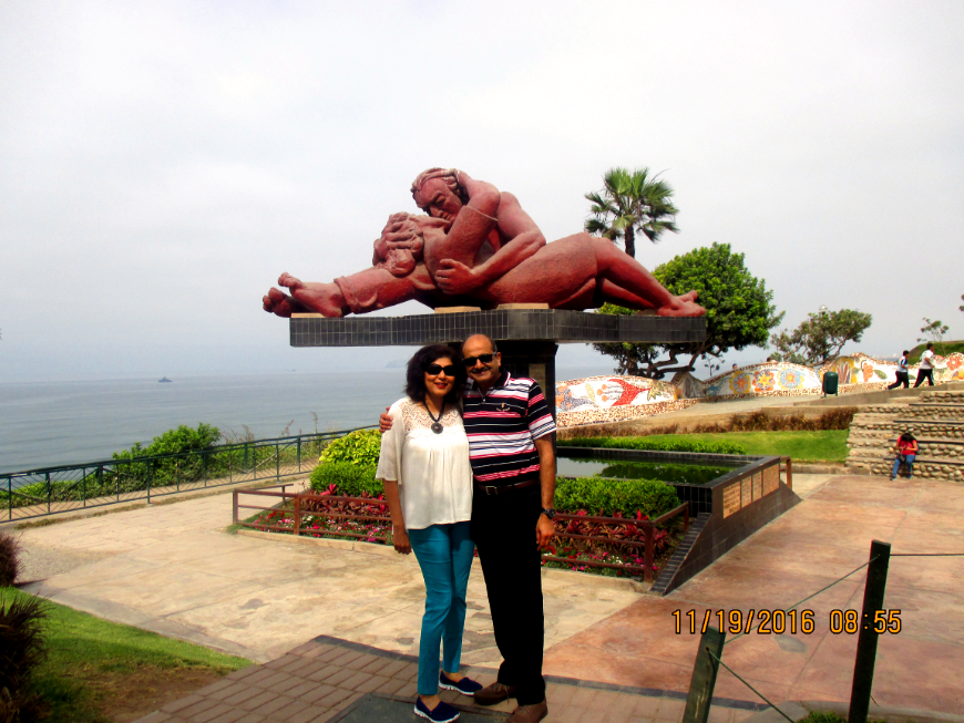 Peru Group Tour Image: Mr. and Mrs. Nayak pose in front of the park's famous statue — a couple engaged in a passionate kiss.