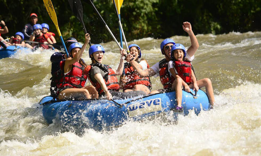 Is It Safe to Travel in Costa Rica Image: A group of whitewater rafters is seen laughing, smiling, and having fun.