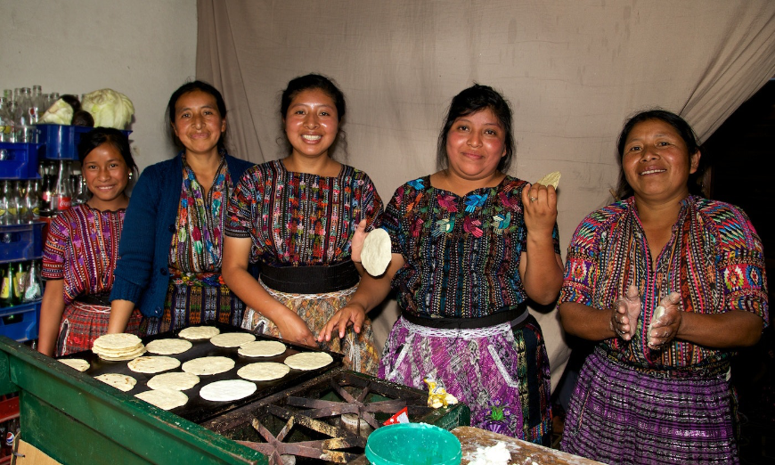 Sustainable Tourism Image: Women in colorful outfits prepare food at the Sololá Market in Lake Atitlán, Guatemala.