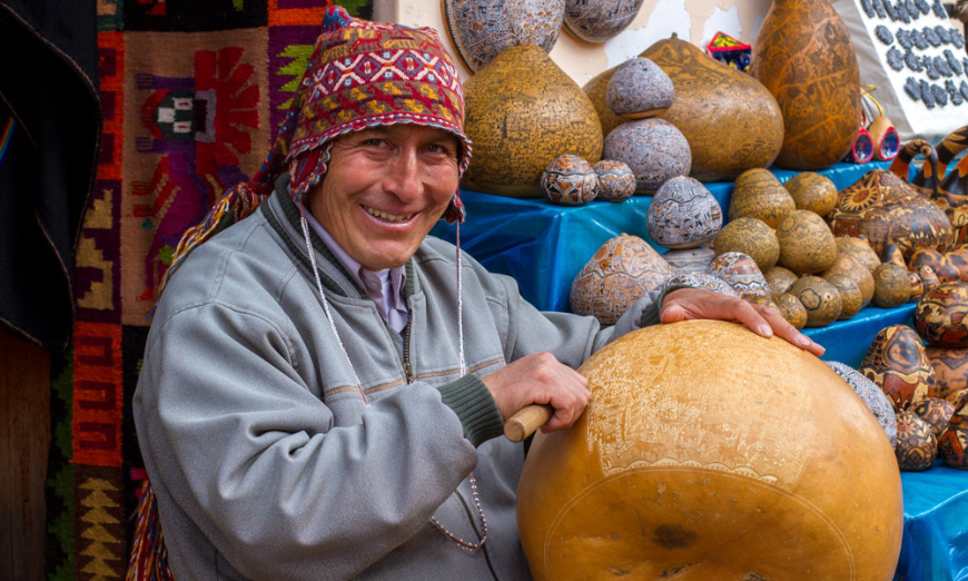 Sustainable Travel In Peru Image: A gentleman is intricately hand carving an oversized gourd.