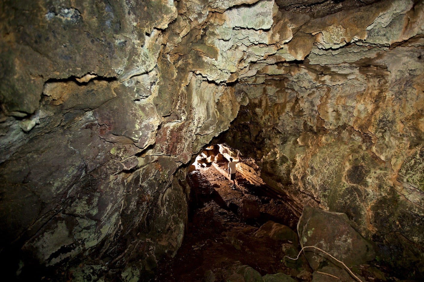 Photos Of The Galápagos Image: A lone traveller wearing dark shorts and a light t-shirt walks through a cave.