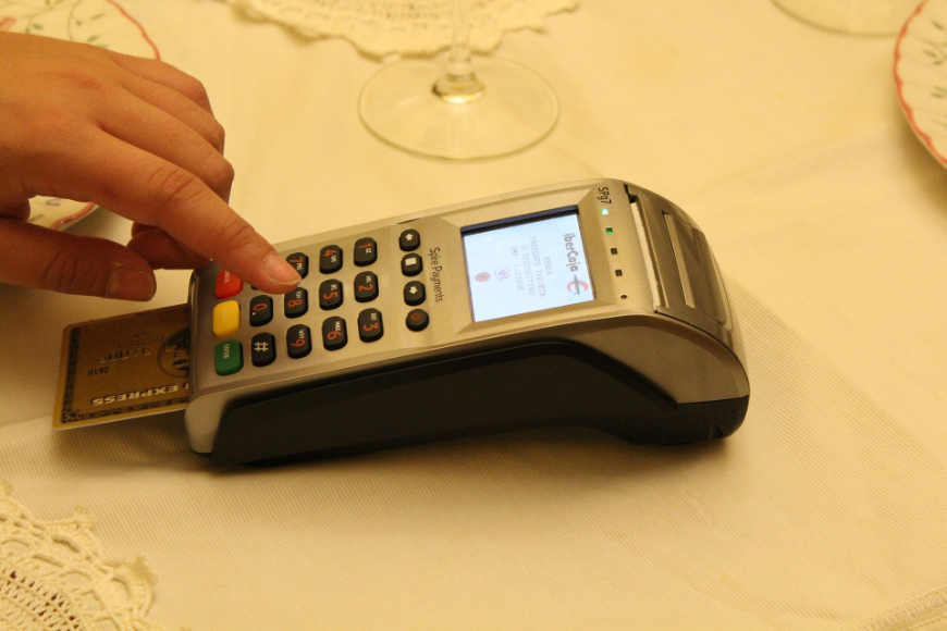 Tropical Holiday Image: An American Express gold card is put into a credit card machine to indicate how it costs more to take a tropical holiday getaway during the holiday season.
