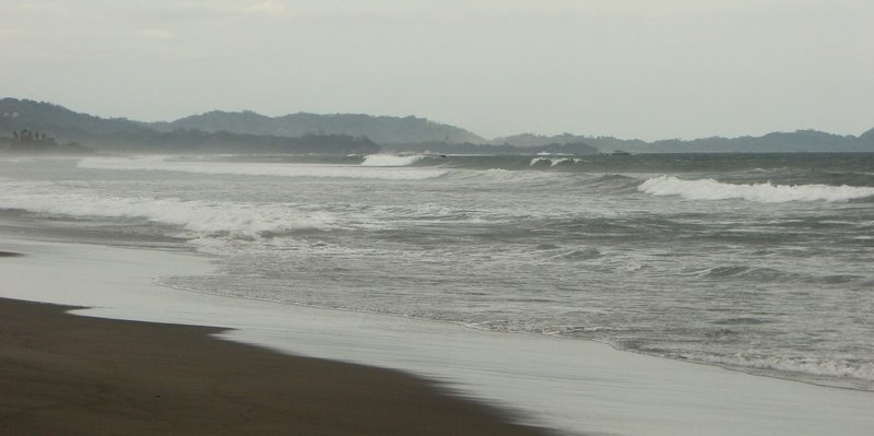Grey sand and rolling surf along the beach at Ostional