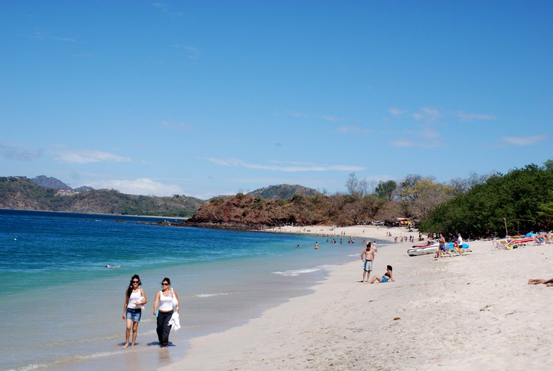 Two people walking along the shoreline of Playa Conchal
